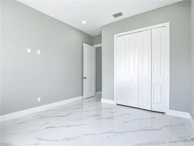 Unfurnished bedroom with light marble finish flooring, recessed lighting, and a closet