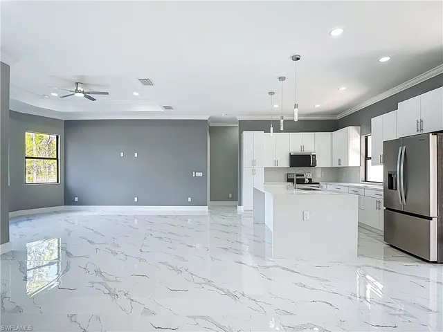 Kitchen featuring stainless steel appliances, pendant lighting, open floor plan, white cabinetry, and ceiling fan