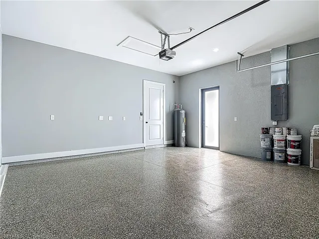 Garage with electric panel, water heater, and a textured wall