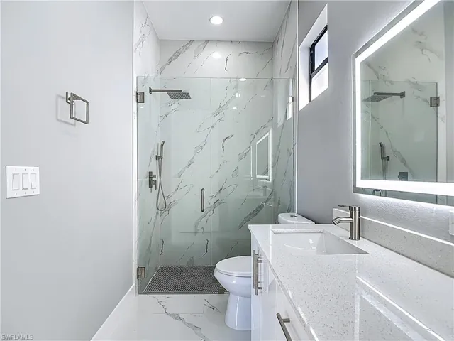 Full bathroom featuring vanity, a marble finish shower, and marble look tile flooring