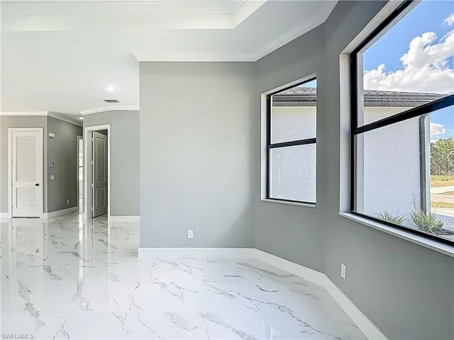 Unfurnished room with crown molding and light marble finish floors