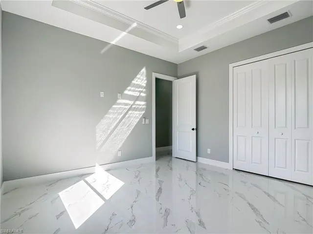 Unfurnished bedroom with ceiling fan, ornamental molding, a raised ceiling, a closet, and recessed lighting