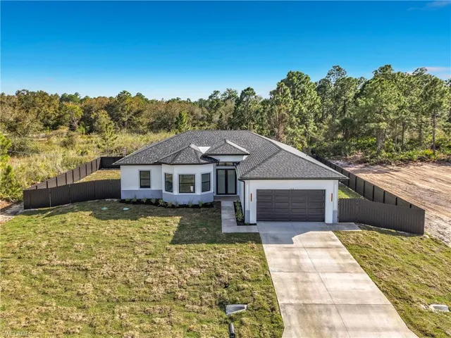 View of front of property with stucco siding, driveway, a garage, and roof with shingles