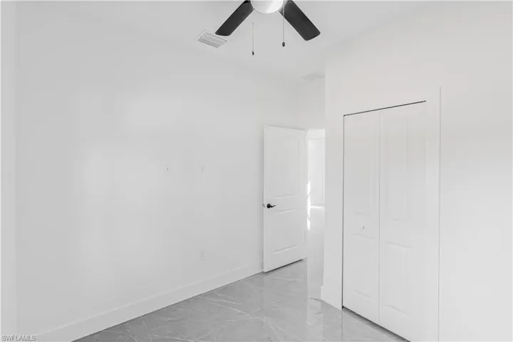 Unfurnished bedroom featuring light marble finish floors, a closet, and ceiling fan