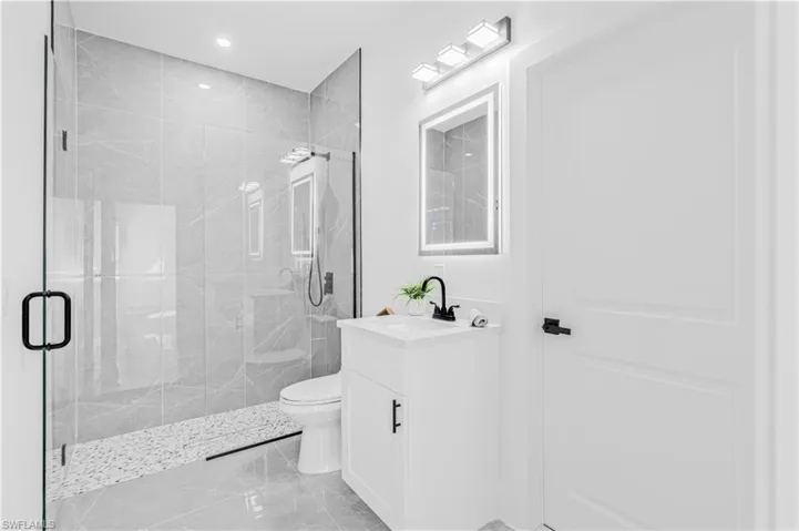 Bathroom featuring a marble finish shower, vanity, light marble finish flooring, and recessed lighting
