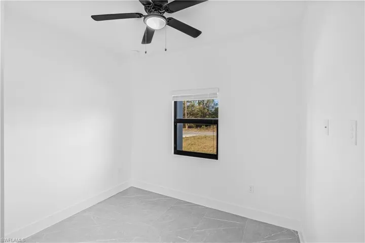 Spare room featuring a ceiling fan and light marble finish floors