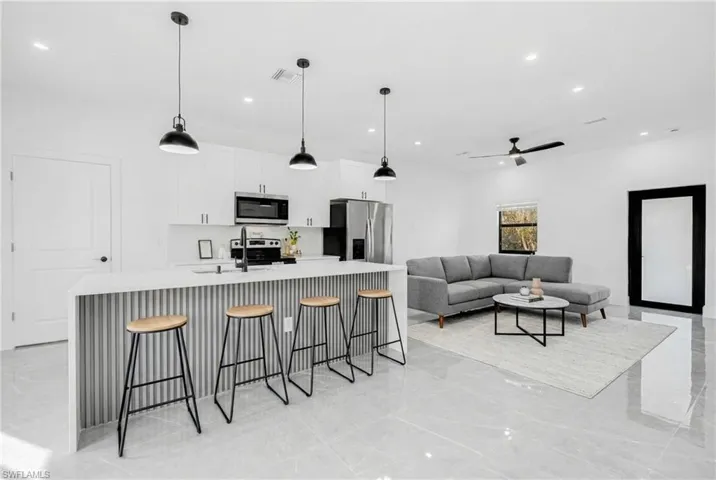 Kitchen featuring an island with sink, a breakfast bar area, hanging light fixtures, light stone countertops, and recessed lighting