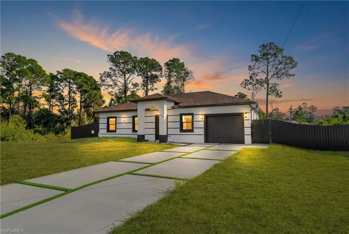 View of front of home with concrete driveway, an attached garage, and stucco siding