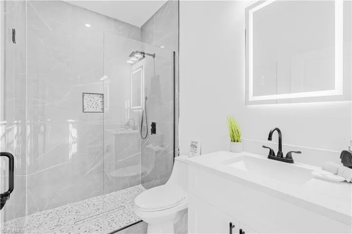 Full bath featuring a marble finish shower and vanity
