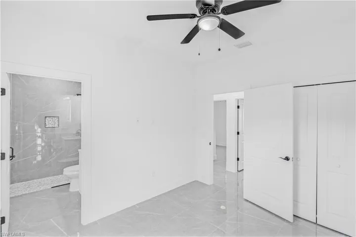 Unfurnished bedroom with light marble finish flooring, ceiling fan, and a closet