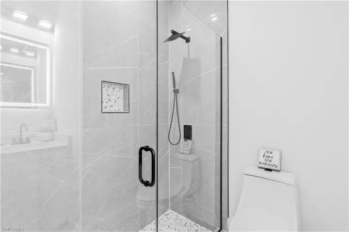 Full bath featuring a marble finish shower and toilet