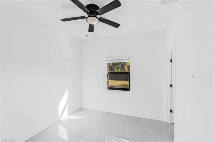 Empty room with light marble finish flooring and a ceiling fan