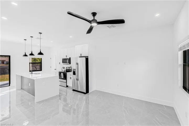 Kitchen featuring hanging light fixtures, stainless steel appliances, light marble finish floors, recessed lighting, and light stone countertops