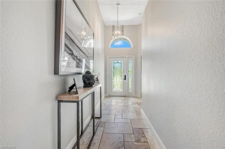 Doorway to outside featuring a notable chandelier and light tile patterned floors