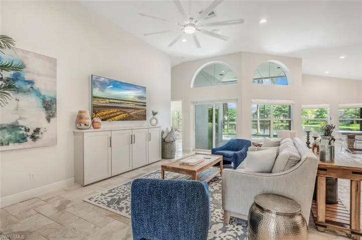 Tiled living room with ceiling fan and high vaulted ceiling