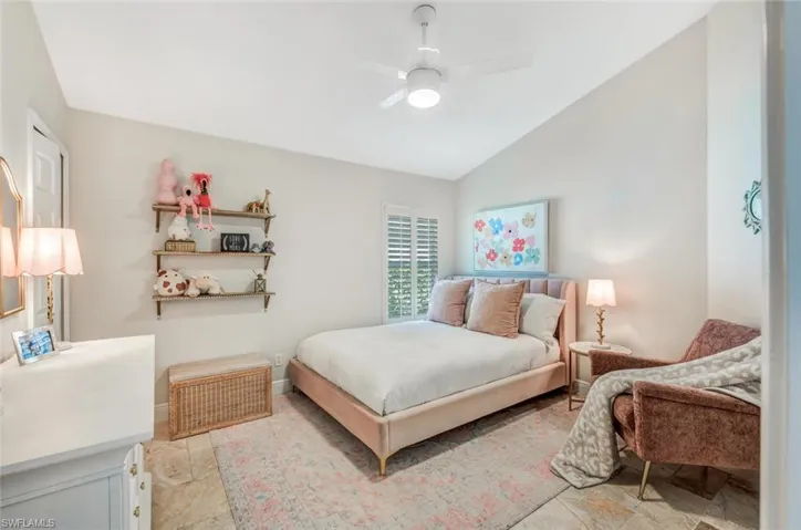 Bedroom with ceiling fan, light tile patterned flooring, and lofted ceiling