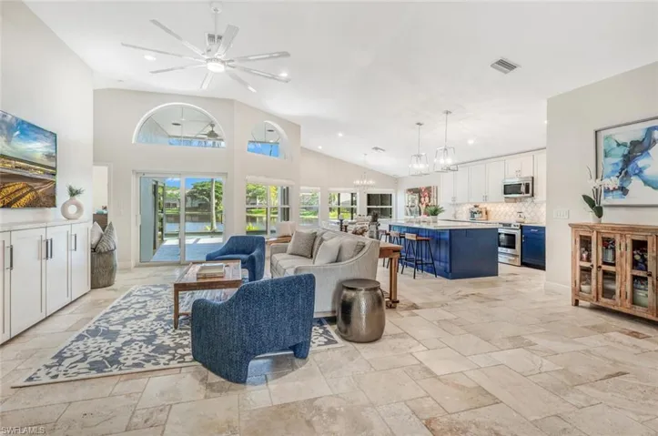 Living room featuring light tile patterned flooring, high vaulted ceiling, and ceiling fan with notable chandelier