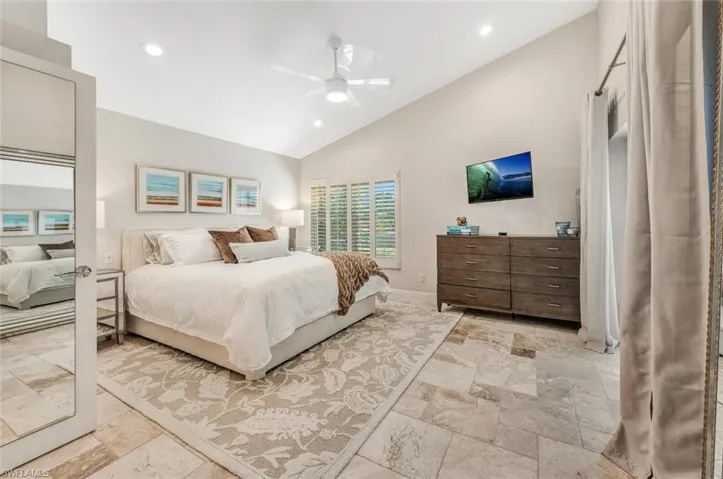 Bedroom with high vaulted ceiling, light tile patterned floors, and ceiling fan