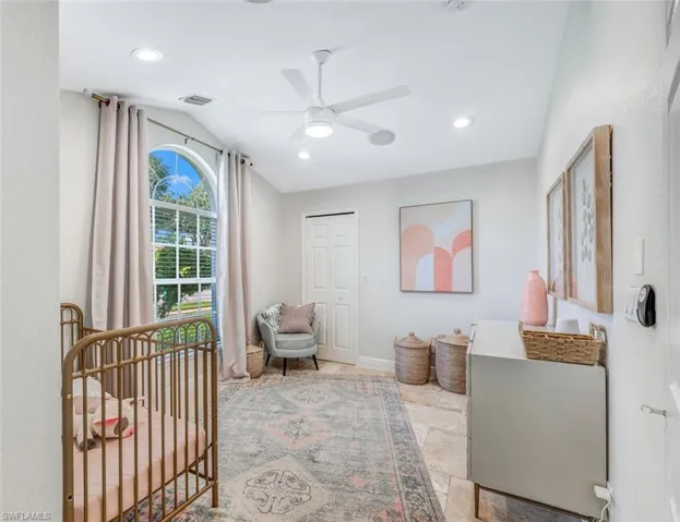 Bedroom with light tile patterned flooring, lofted ceiling, a crib, a closet, and ceiling fan