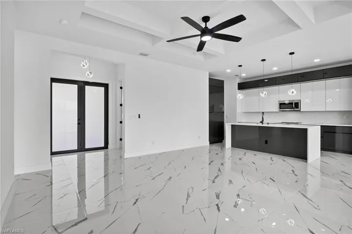 Kitchen with modern cabinets, coffered ceiling, white cabinets, beamed ceiling, and decorative light fixtures