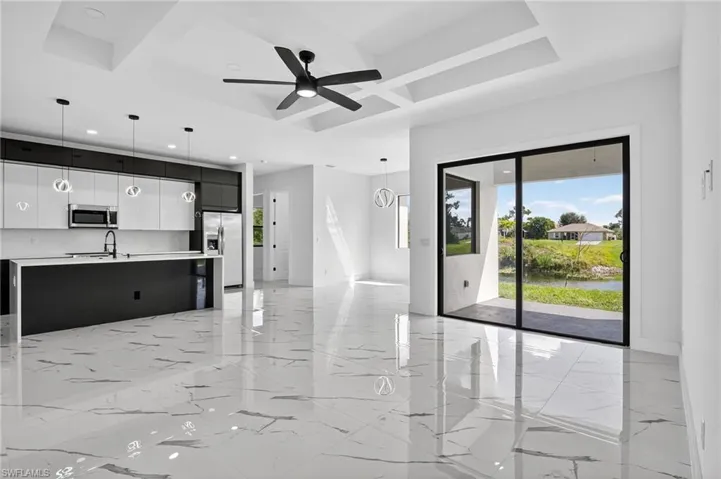 Unfurnished living room featuring coffered ceiling, light marble finish flooring, beam ceiling, and a ceiling fan