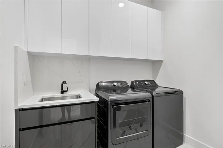 Laundry room featuring cabinet space, separate washer and dryer, and laundry tub