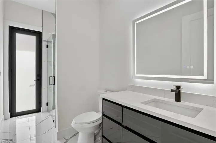 Full bathroom #2 featuring vanity, light marble finish floors, and a marble finish shower