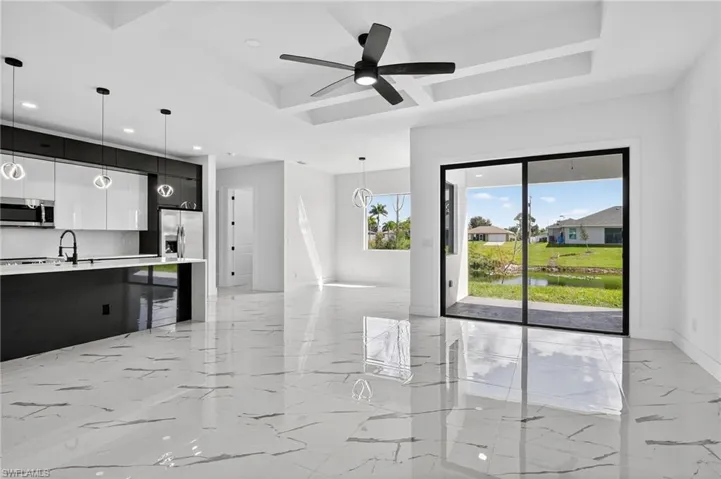 Unfurnished living room with light marble finish flooring, ceiling fan, a water view, a tray ceiling, and recessed lighting