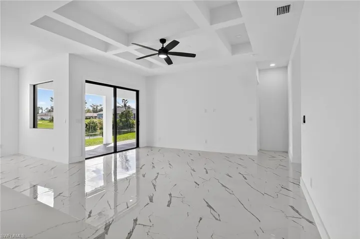 Spare room featuring light marble finish floors, coffered ceiling, beam ceiling, and a ceiling fan