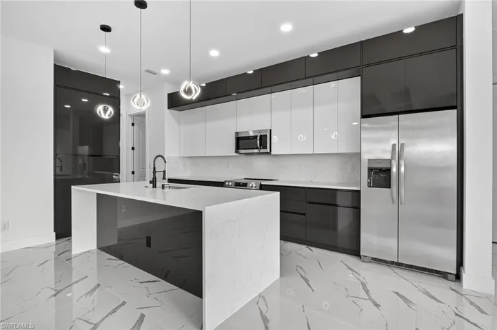 Kitchen with modern cabinets, white cabinets, stainless steel appliances, tasteful backsplash, and pendant lighting