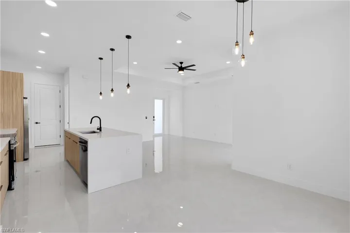 Kitchen featuring hanging light fixtures, sink, ceiling fan, and a kitchen island with sink