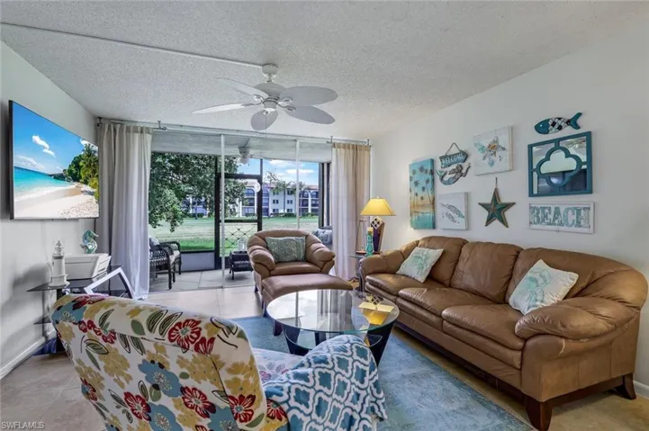 Living room featuring ceiling fan, light tile patterned flooring, and a textured ceiling