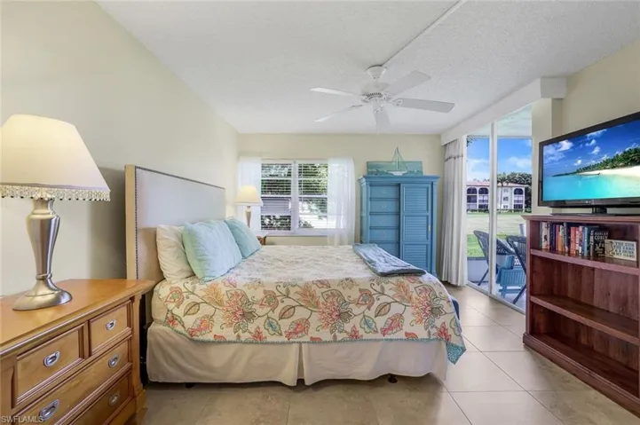 Tiled bedroom featuring ceiling fan, access to outside, and a textured ceiling