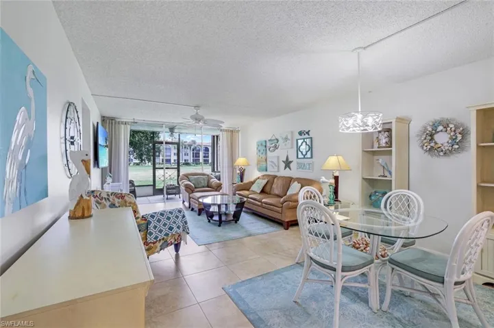 Tiled dining space with ceiling fan with notable chandelier and a textured ceiling