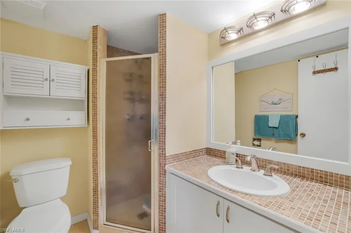 Bathroom featuring a shower with shower door, vanity, and toilet