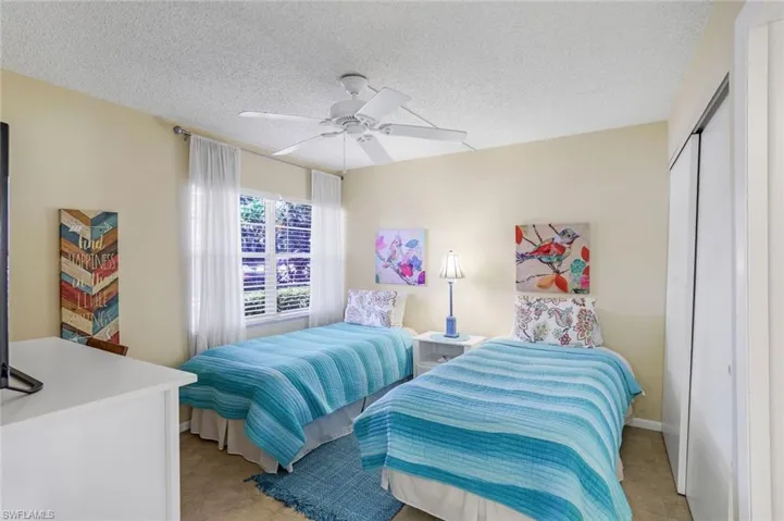 Bedroom featuring light tile patterned flooring, a textured ceiling, a closet, and ceiling fan