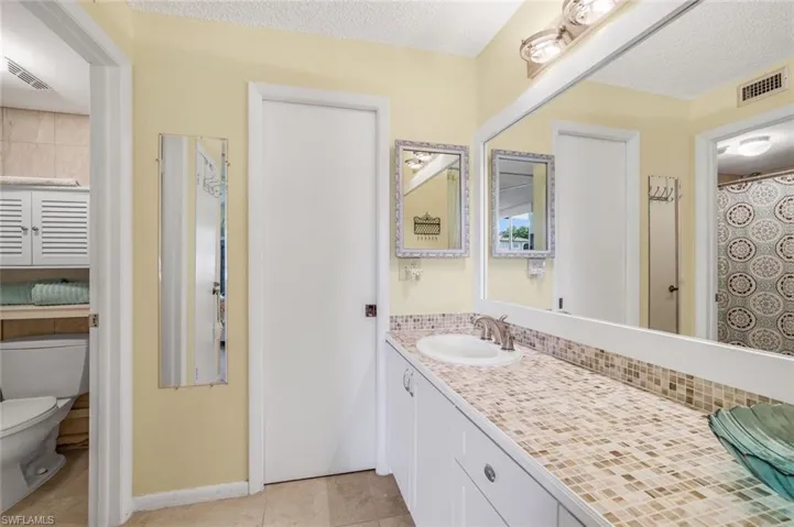 Bathroom featuring a textured ceiling, toilet, vanity, and tile patterned flooring