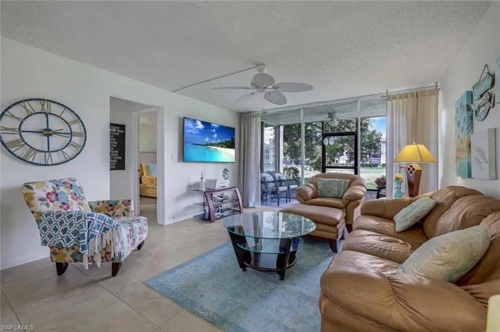 Tiled living room with a wall of windows, a textured ceiling, and ceiling fan