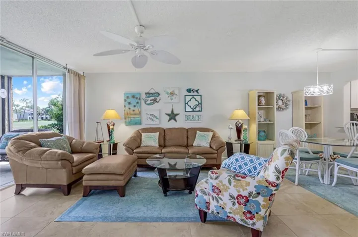 Tiled living room featuring a textured ceiling, expansive windows, and ceiling fan