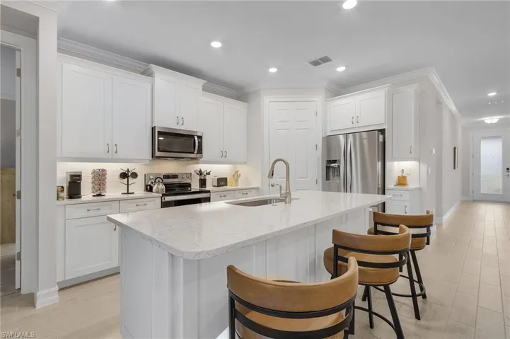Kitchen with a center island with sink, sink, white cabinetry, and stainless steel appliances