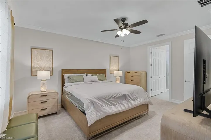 Bedroom featuring ceiling fan, a closet, light colored carpet, and ornamental molding