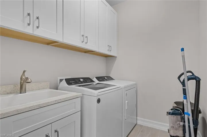 Washroom with cabinets, independent washer and dryer, light hardwood / wood-style flooring, and sink