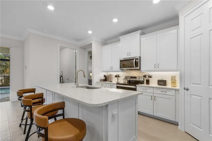 Kitchen with white cabinetry, sink, an island with sink, and stainless steel appliances