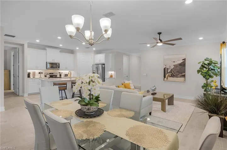 Dining area with crown molding, light hardwood / wood-style flooring, and ceiling fan with notable chandelier