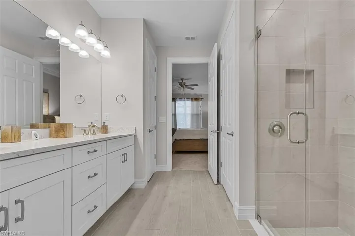 Bathroom with ceiling fan, hardwood / wood-style floors, vanity, and a shower with shower door