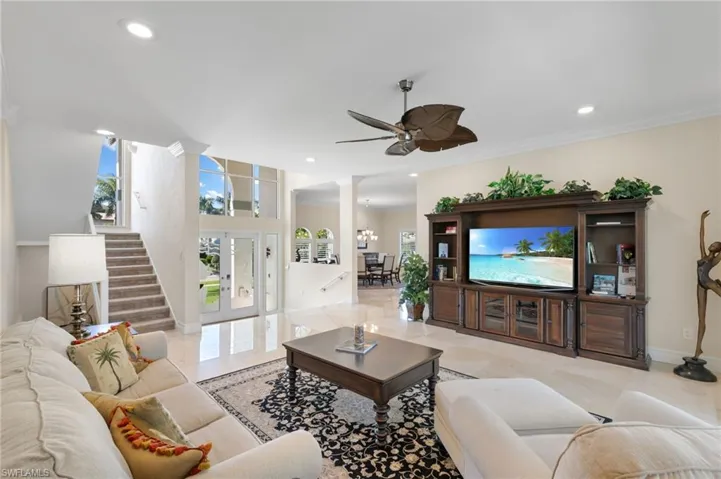 Living room featuring ornate columns, ornamental molding, recessed lighting, stairs, and a chandelier