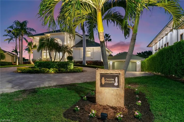 Mediterranean / spanish-style house featuring curved driveway, stucco siding, a front lawn, a garage, and an outdoor structure