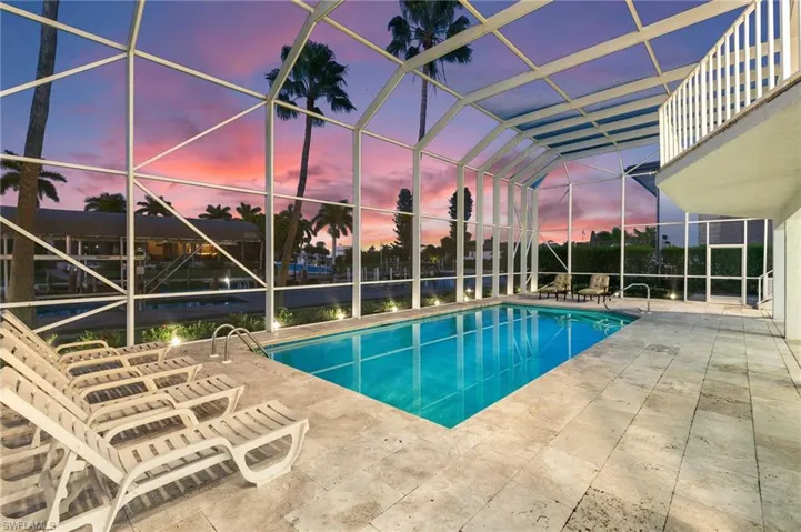 Swimming pool with a sunroom, glass enclosure, and a patio