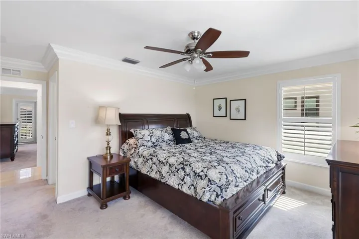 Bedroom featuring light colored carpet, crown molding, and a ceiling fan
