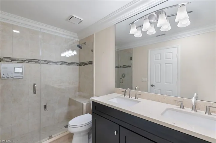 Full bath with ornamental molding, a stall shower, and double vanity